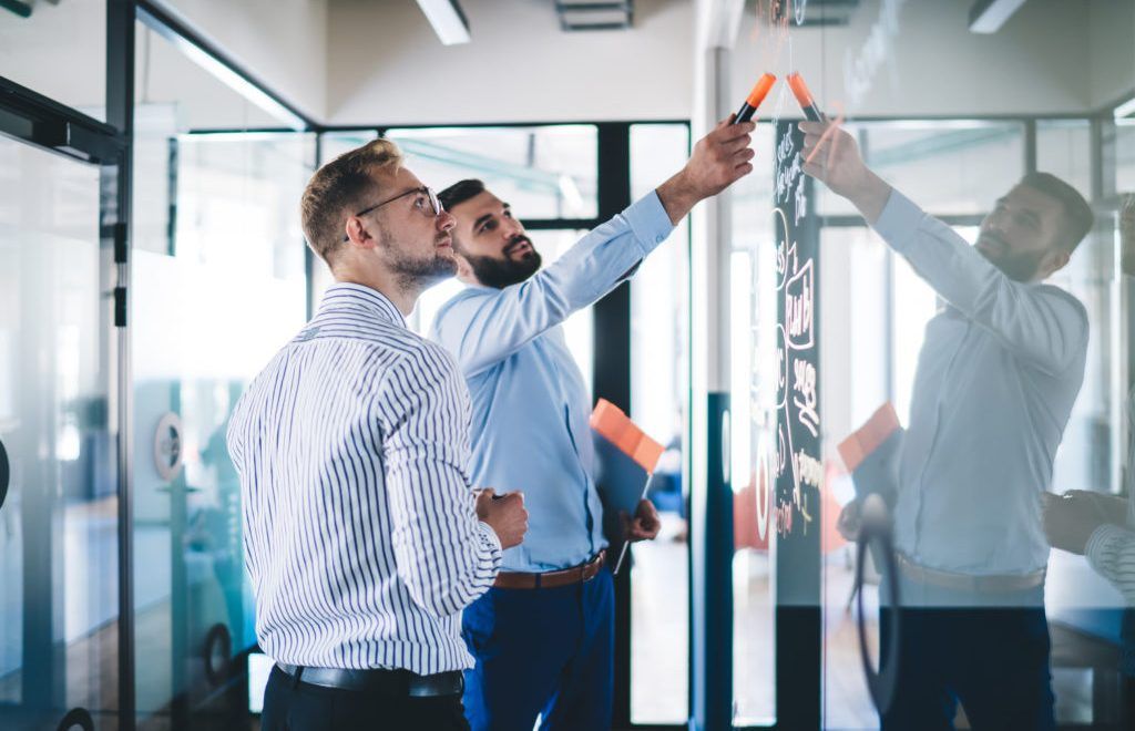 Confident male employee pointing on notes standing with colleagu