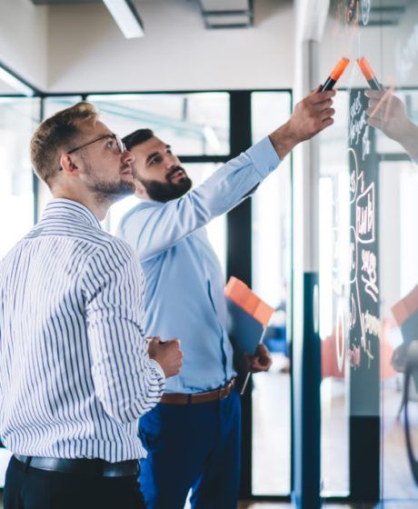 Confident male employee pointing on notes standing with colleagu